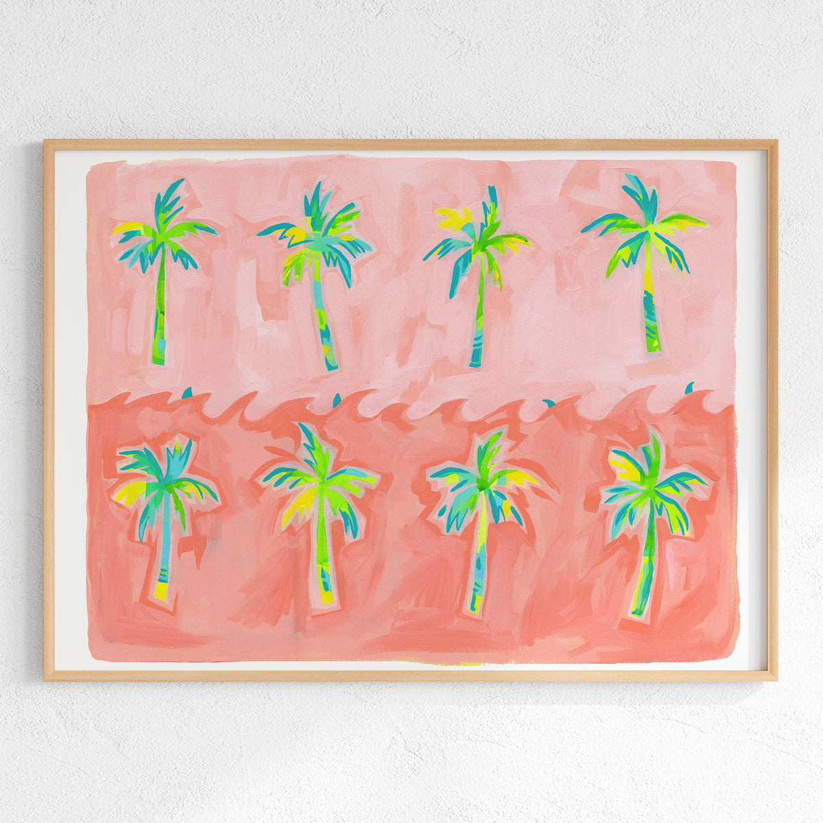 A framed art print featuring a whimsical illustration of eight palm trees in vibrant green, blue, and yellow tones against a split pink and coral background, mounted on a textured white wall.