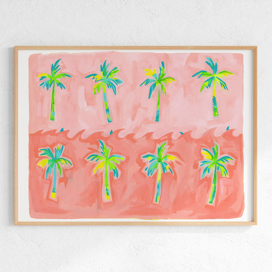 A framed art print featuring a whimsical illustration of eight palm trees in vibrant green, blue, and yellow tones against a split pink and coral background, mounted on a textured white wall.