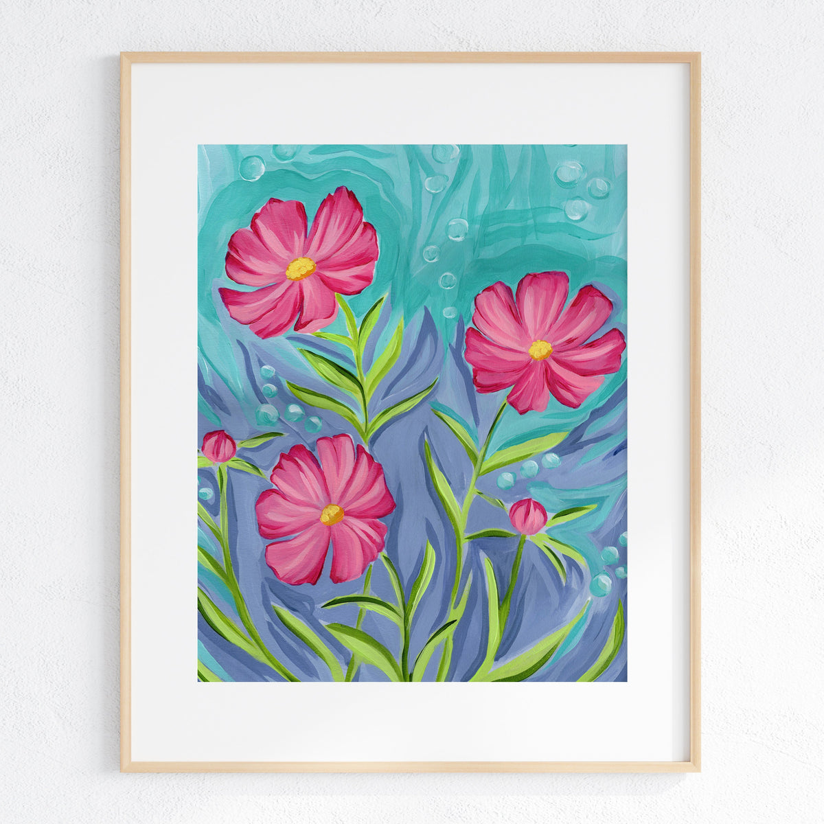 A framed art print featuring three pink cosmos flowers with green stems against a textured teal and blue background, displayed in a light wood frame on a white wall.